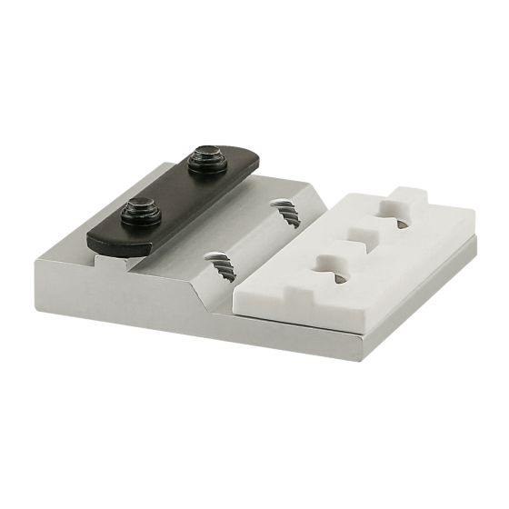 square, flat metal piece with a raised left side and a black, rectangular mounting plate on the top left with two screws through it, and a white, rectangular mounting pad on the top right with two holes in it.