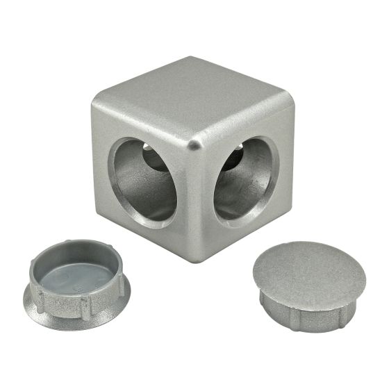 side view of a square, aluminum block with large holes in the two sides that are showing and round caps for the holes sitting next to it