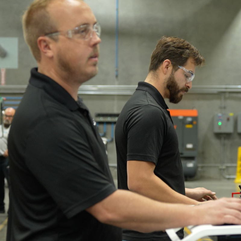 two employees working in the machine shop with safety glasses