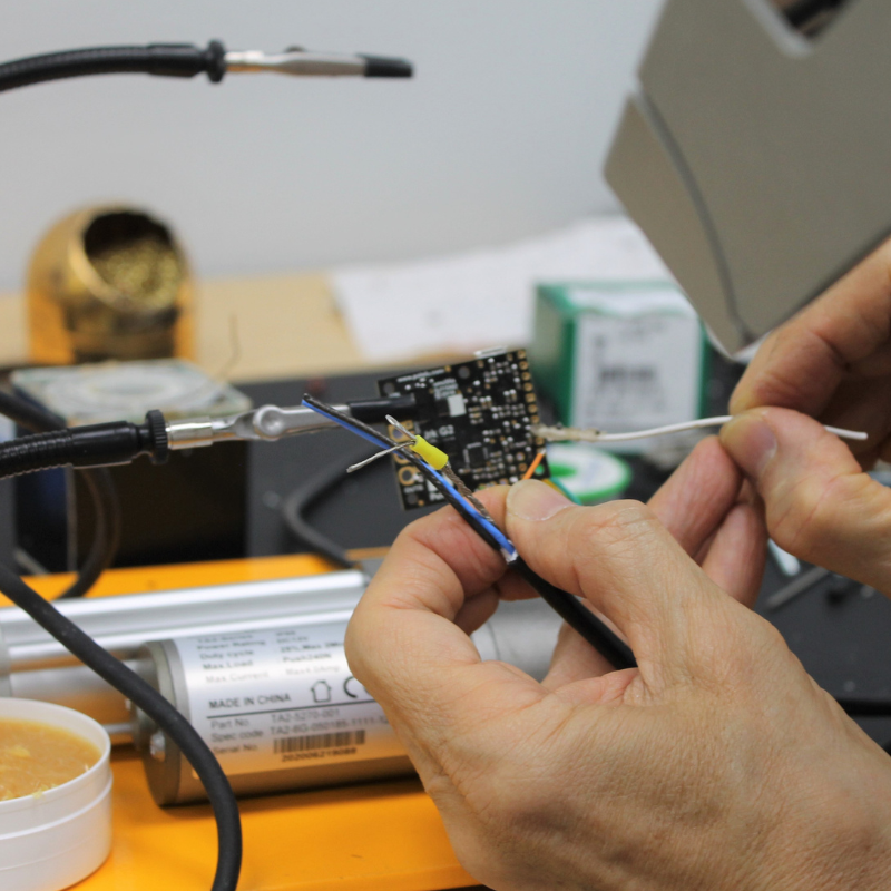 Two hands connecting wiring to a circuit board