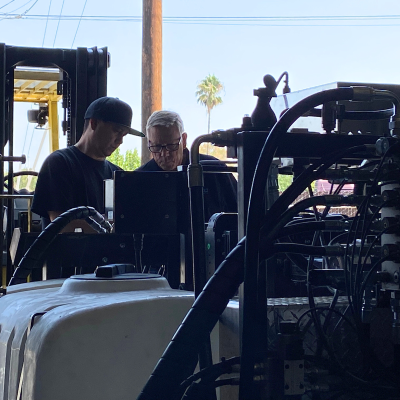 Two employees looking at a screen and machinery