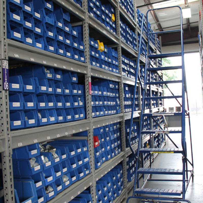 Blue bins on gray shelving with a blue ladder